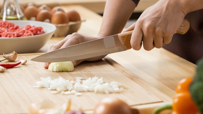 Person chopping a white onion