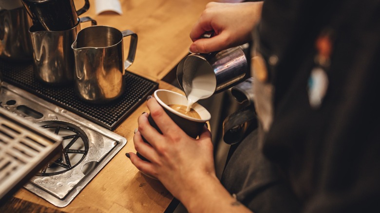 A barista pouring steamed milk