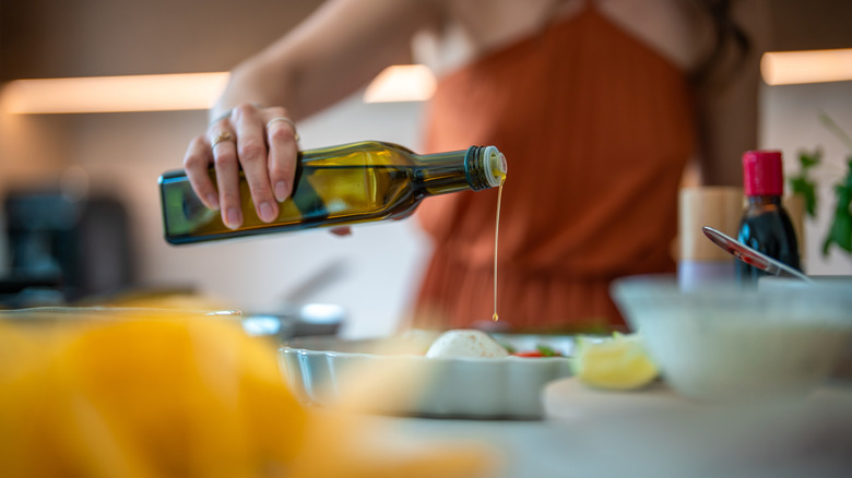 Woman pouring olive oil from a tinted glass container