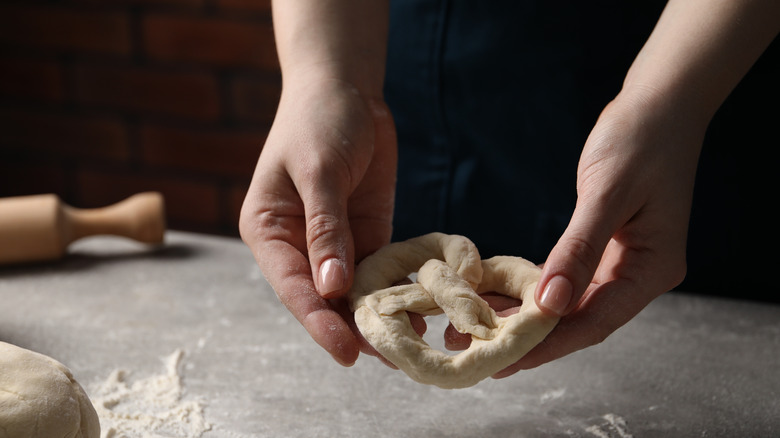 caucasian hands working with pretzel dough