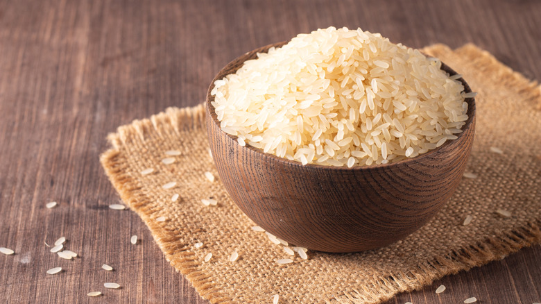 Uncooked white rice in a wooden bowl.