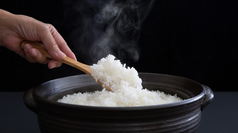 An individual cooking rice in a clay pot.