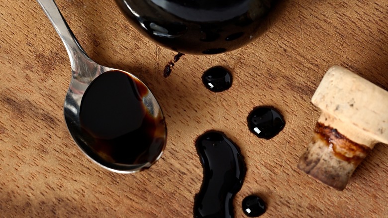 Drops of aged balsamic on a spoon and a wooden table