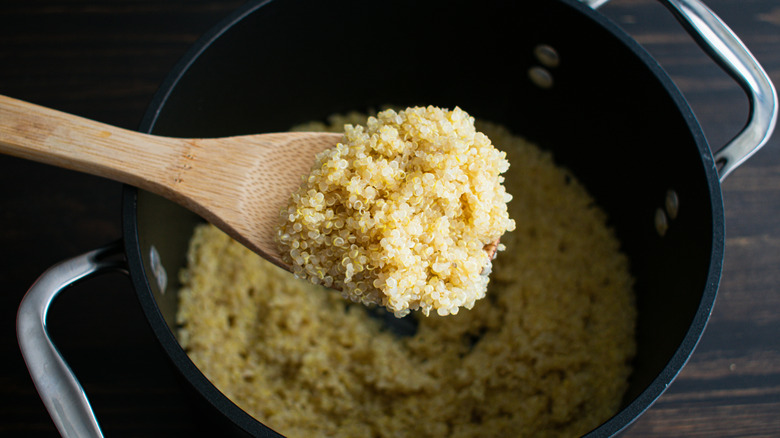 wooden spoon scooping out white quinoa