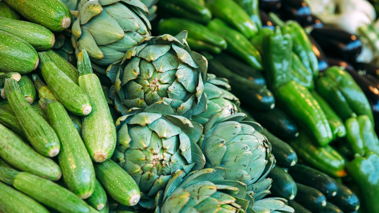 artichokes nestled among other veggies in produce section