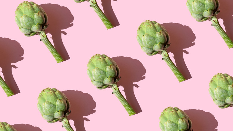 small artichokes with long stems on pink background