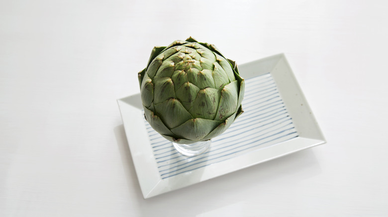 artichoke in small glass jar on rectangular plate