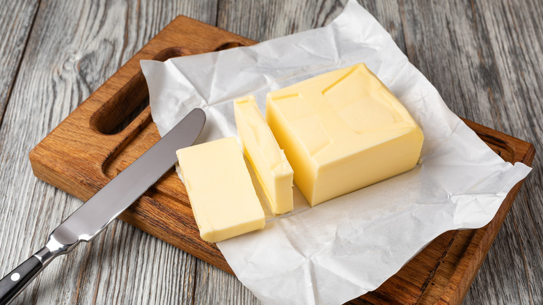 Fresh butter slices on a wooden cutting board.