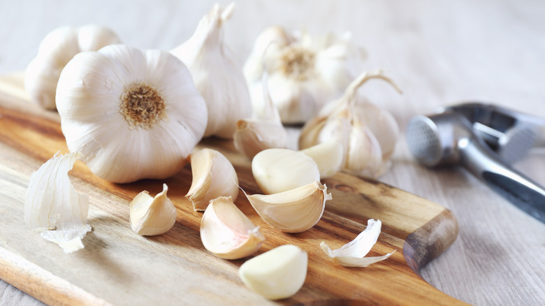 Garlic bulbs and cloves on a wooden cutting board.