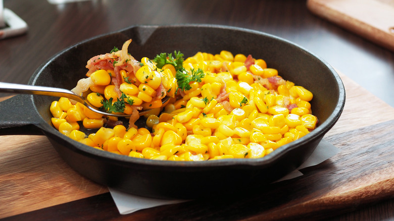 Corn in a cast iron skillet with parsley and bacon.