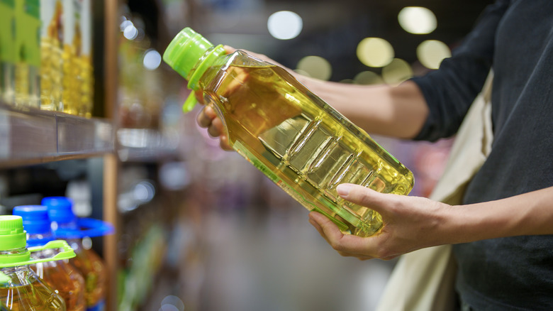 A person holding bottle of oil in grocery store