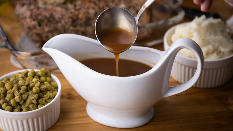 Gravy pouring from a spoon into a gravy boat.