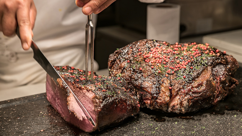 Person carving a seasoned beef roast
