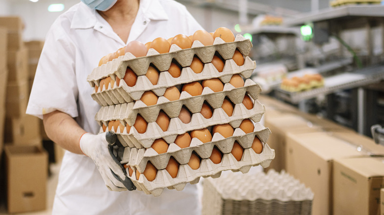 Woman holding several stacked cartons of eggs