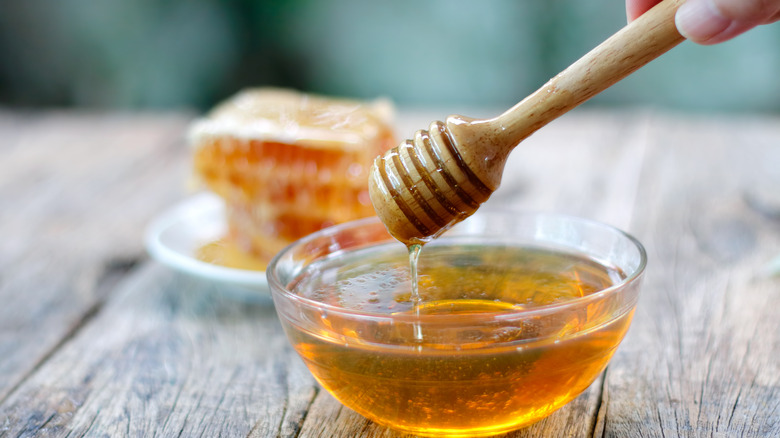 Honey in a bowl with hand