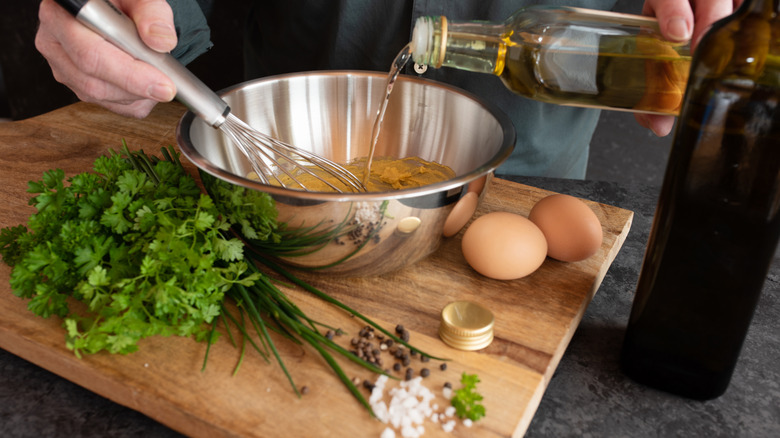 hands preparing gribiche in a bowl with a whisk