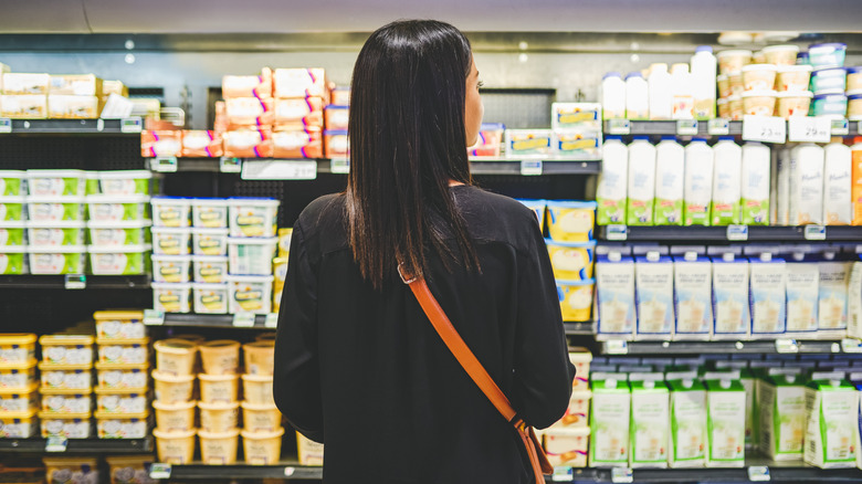 Person standing in front of the butter and dairy section in a grocery store