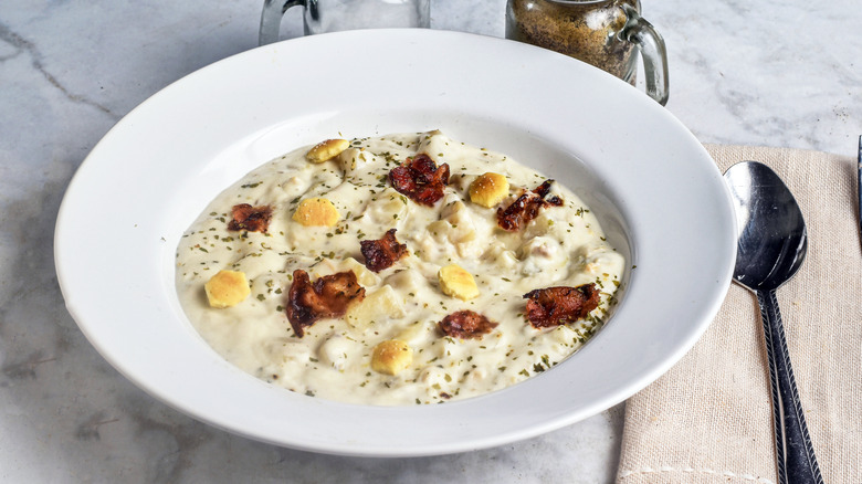 white bowl of creamy soup with bacon and oyster crackers
