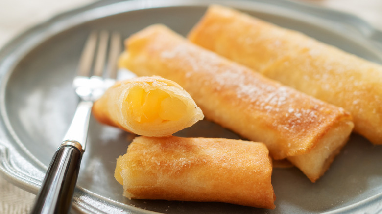 Apple pie egg rolls on a gray plate with a metal fork