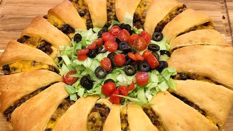 Baked crescent roll taco with lettuce, tomatoes, and olives