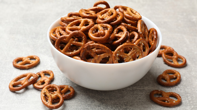 Pretzels spilling out of white bowl on gray countertop.
