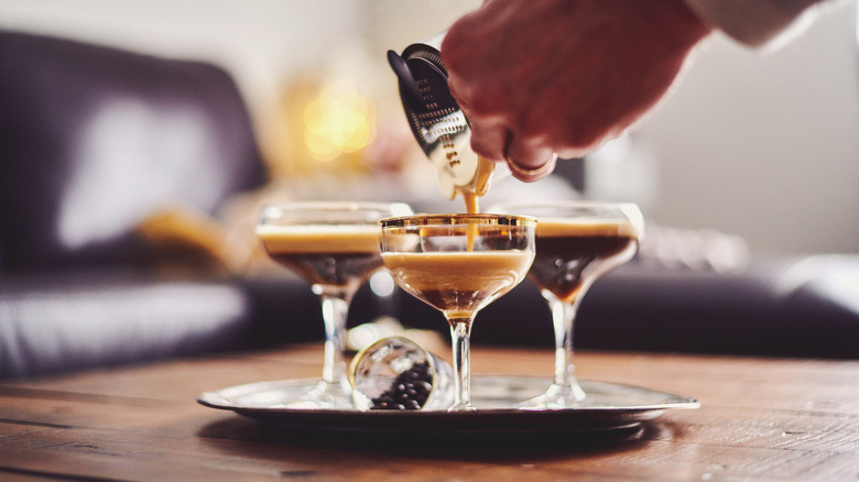 Hands pour espresso martini into a glass