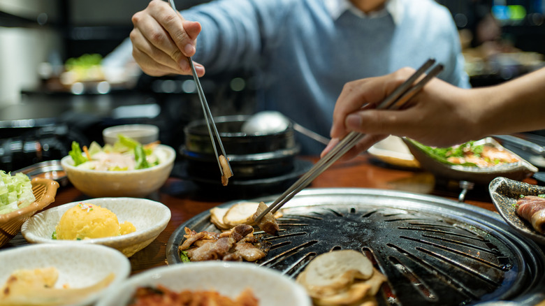 People enjoying Korean BBQ with chopsticks
