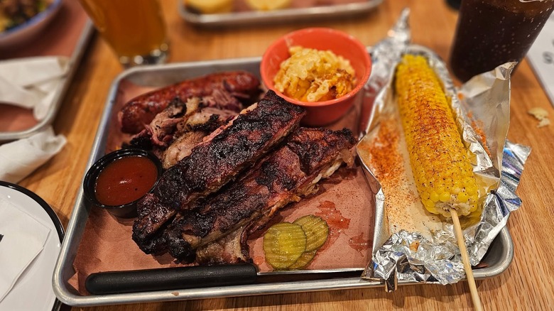 Three meat combo plate with mac and cheese and corn served on a platter at Jim 'N Nick's restaurant