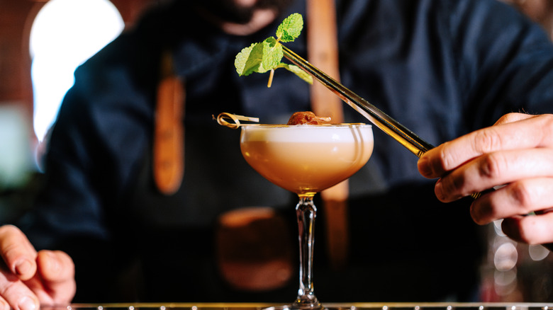 Bartender adding a garnish to a cocktail