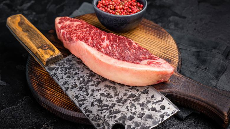 A raw picanha steak sitting on a meat cleaver.