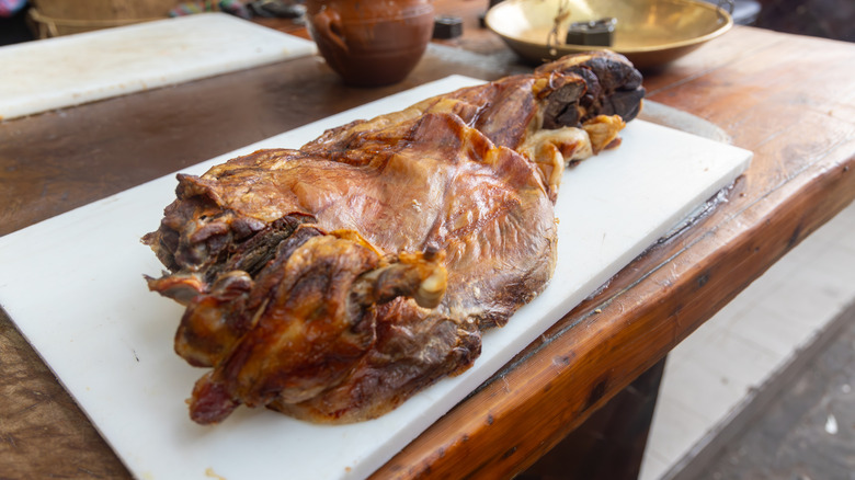 Whole-roasted lamb on a white plastic cutting board