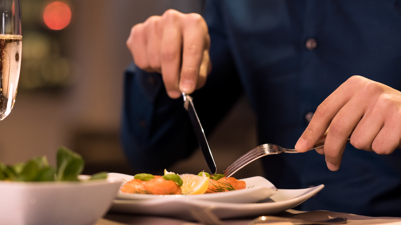 Close up of man cutting food with fork and knife