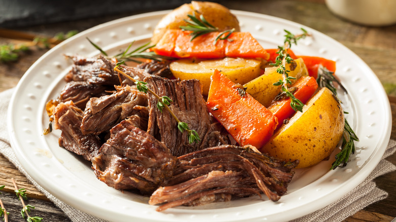 A bowl of homemade, slow-cooked pot roast with carrots and potatoes.