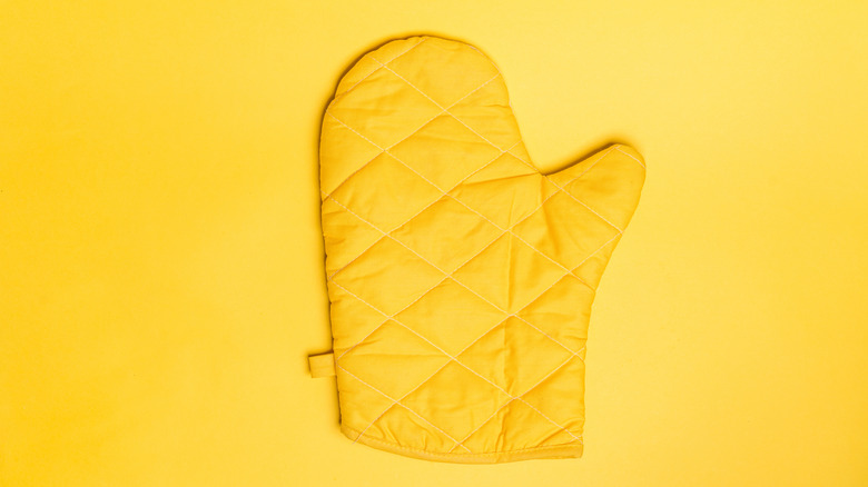 Yellow oven mitt on yellow background.