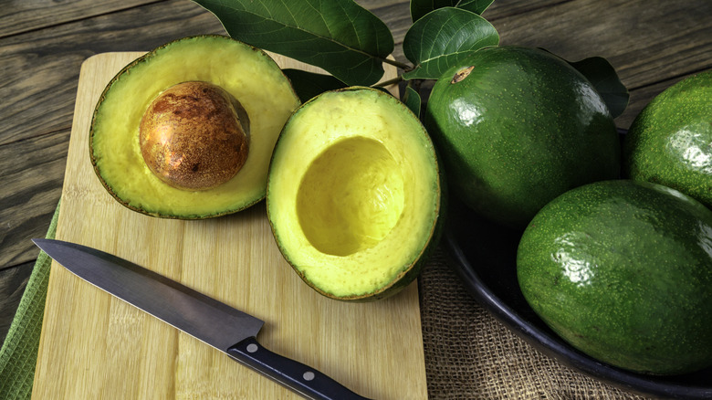Halved avocado with whole avocados in the background