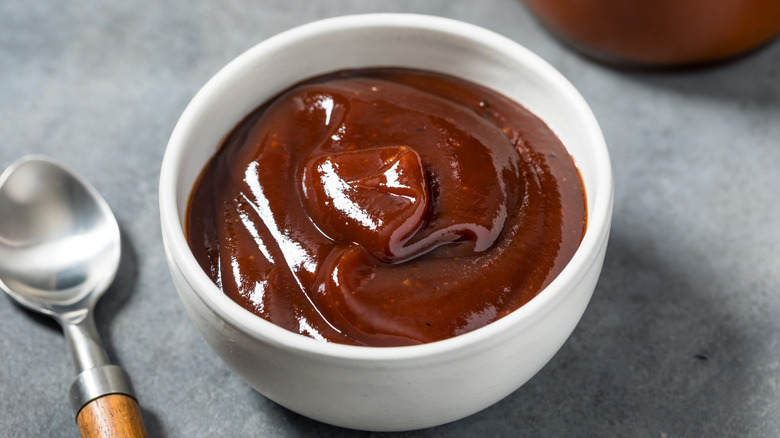 Barbecue sauce in a white ramekin with a spoon on the side
