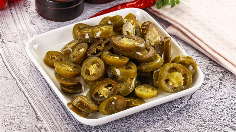 Close up of pickled jalapenos in a white square dish