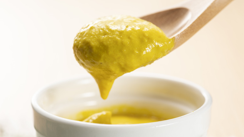 Close up of yellow mustard on a wooden spoon