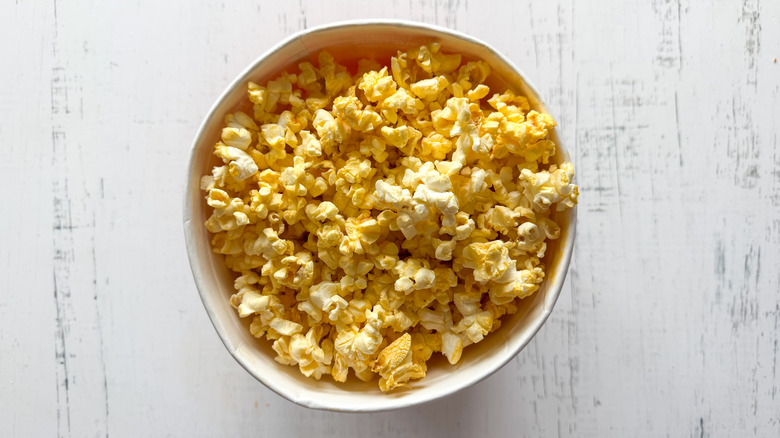 Container of popcorn on white surface