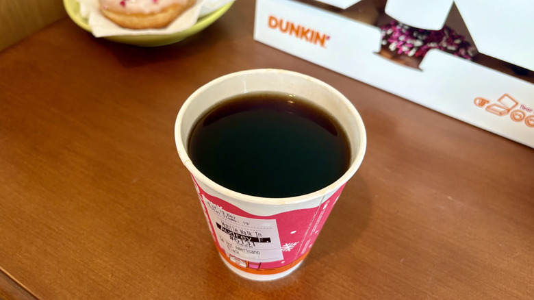 An Americano from Dunkin' with a Dunkin' box and donut in background