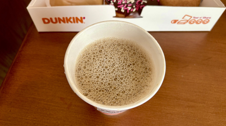 A cappuccino from Dunkin' with a Dunkin' box in the background