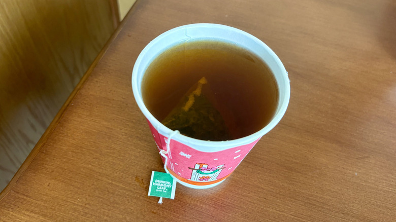 A Harmony Leaf Green Tea from Dunkin' on a wood surface