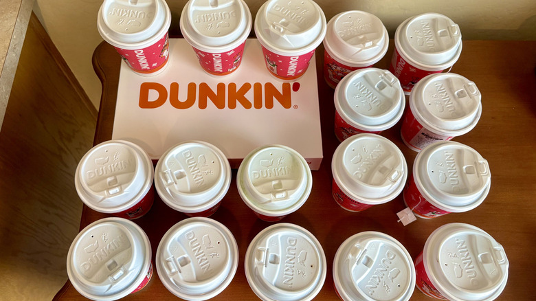 A group of hot drinks from Dunkin' on brown table