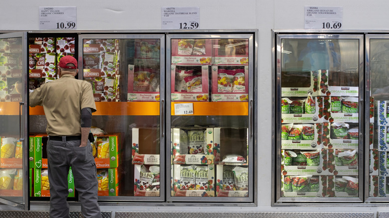 Person picking out frozen fruit in a Costco's frozen foods aisle