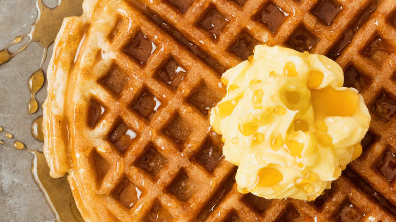 close-up of a waffle with a dollop of butter and syrup