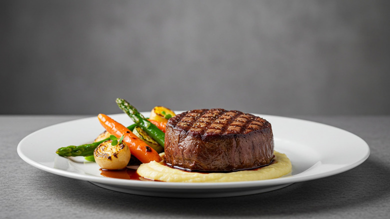 A beef steak in a plate with vegetables and mashed potato