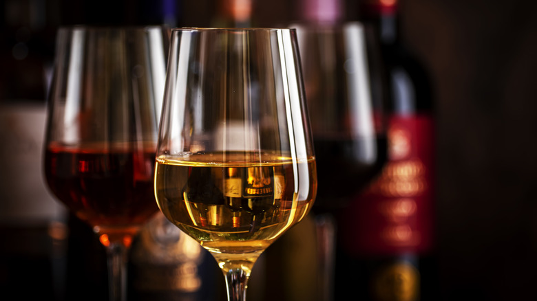 A glass of red wine and a glass of rose wine with more glasses and bottles in the background.