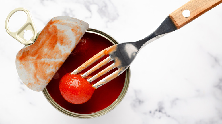 A fork holding a cherry tomato from a can