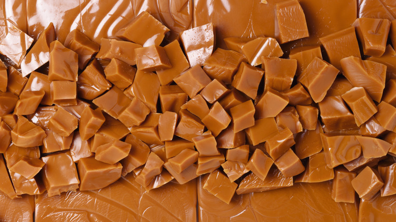 Larges sheets of uncut toffee with chunks of cut toffee sitting on top.