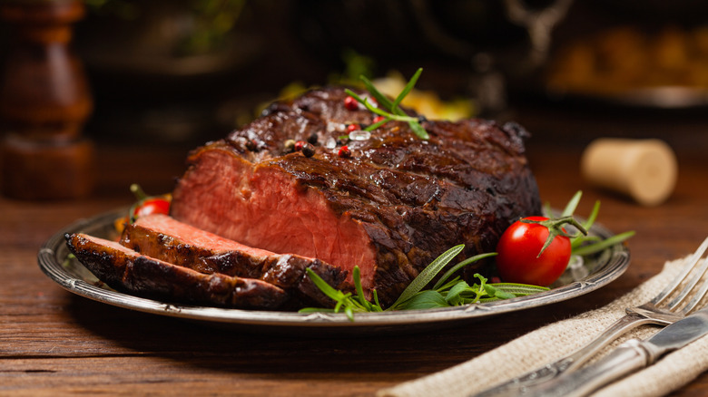 Roasted brisket on a plate with herbs and tomato